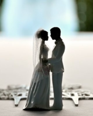 A silhouetted bride and groom cake topper on the tier of a wedding cake