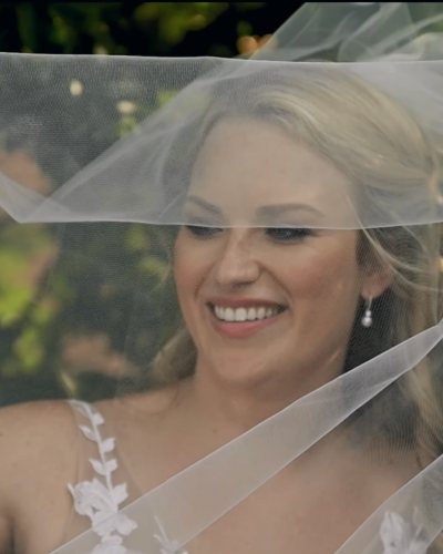 A bride laughing beneath her veil in warm afternoon light