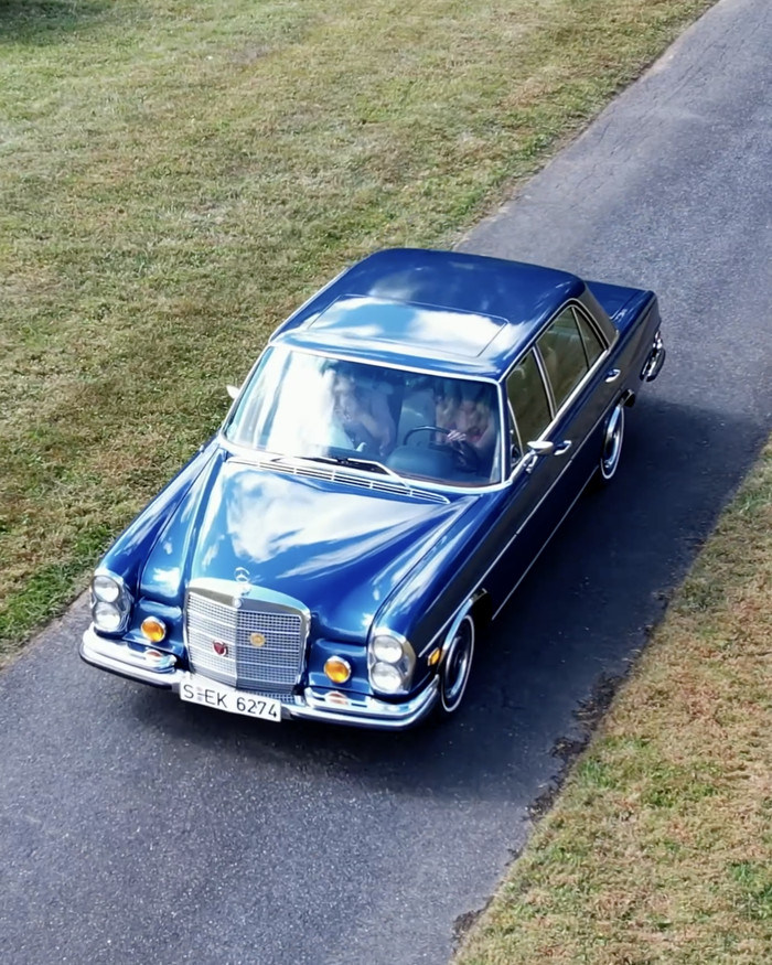 An aerial view of a vintage blue sedan waiting on a driveway